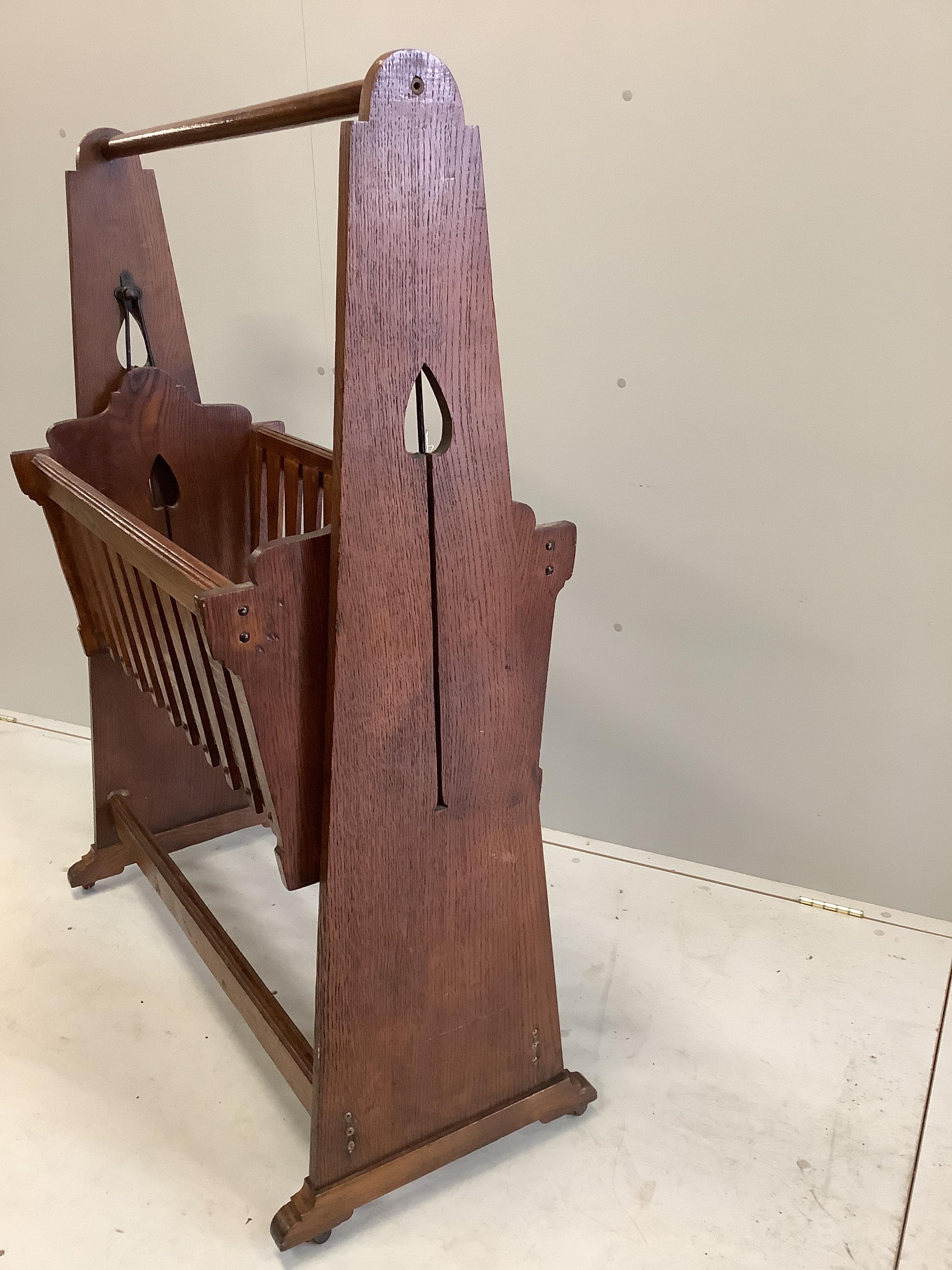 An Arts and Crafts oak rocking crib, width 97cm, height 130cm
